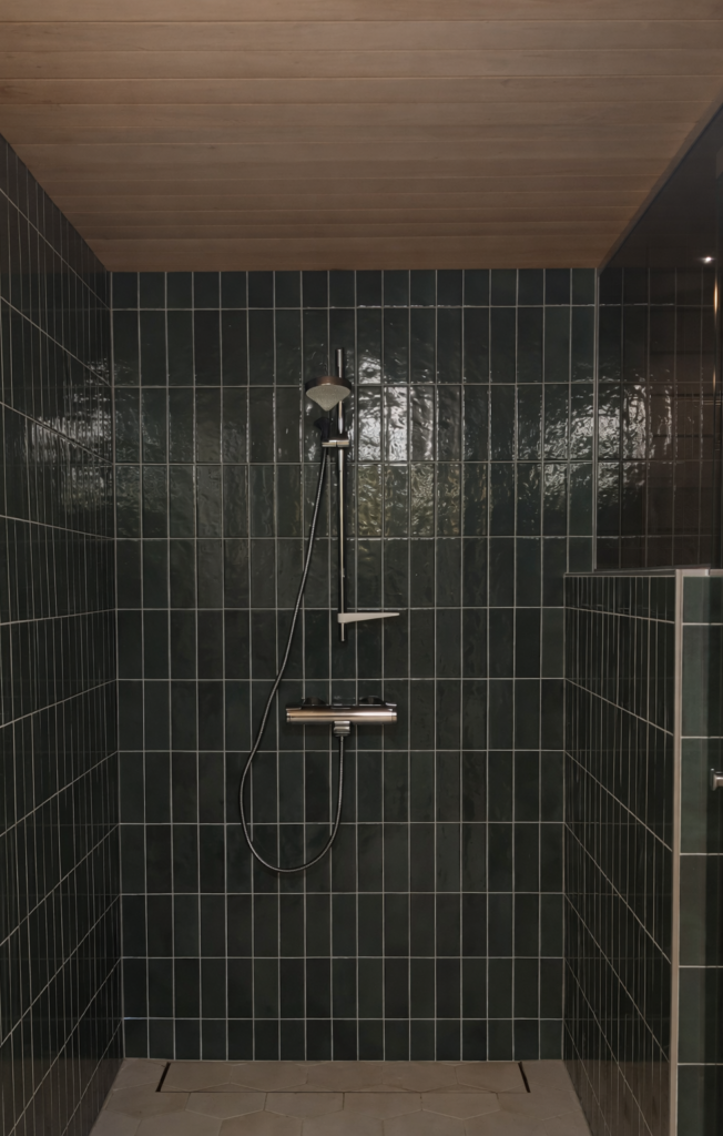 Suihkutila tummanvihreillä kiiltävillä laatoilla ja kromisella suihkusetillä – moderni kylpyhuoneremontti